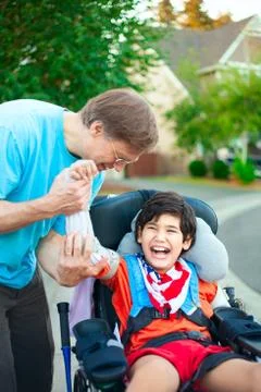 Father helping disabled son adjust arm guards orthotics Stock-Fotos