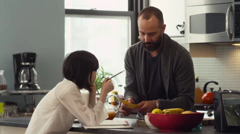 Father helping his daughter with homework in kitchen Stock Footage