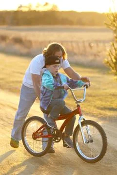 Father Helping his Son Learn to Ride his Bike on Sunny Spring Evening. Stock Photos