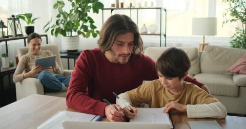 Father helping son doing homework and mother using digital tablet Stock Footage 145231171