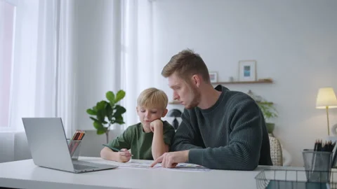 Father helping son doing homework in living room. Smiling child and parent Stock Footage 215077399
