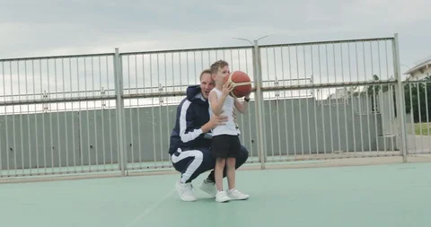 Father helping son to throw the ball into the basket on a sports ground Video stock 122429250