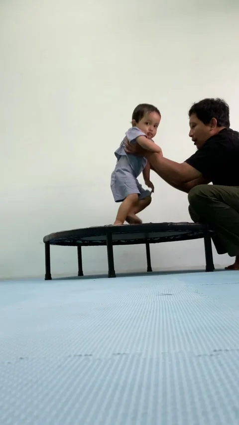 Father Helping Toddler Play on Mini Trampoline Stock Footage 341497465