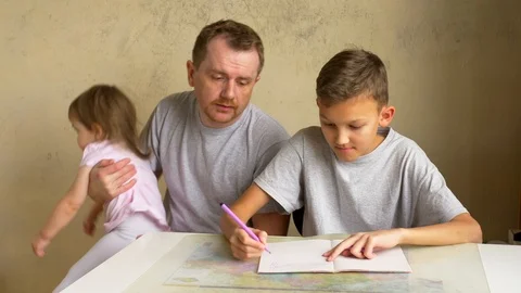 Father helps son with homework, small daughter runs away Stock Footage 99702300