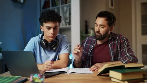 Father helps teenage son to solve math equations, parental support, togetherness Stock Footage 329840468