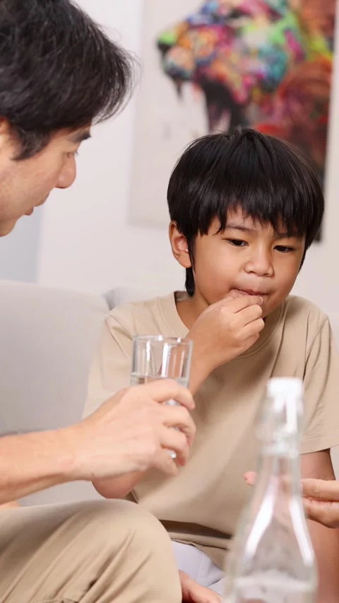 Father Helps Young Son Take Medicine at Home Stockbeeldmateriaal 314876969