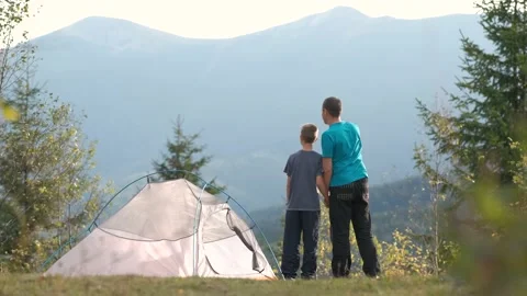 Father with his child son walking together near a tent in summer mountains. Stock Footage 148445238