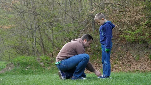 Father on his knees ties the strings of his son, thankful child caress dad head Stock Footage 118190052