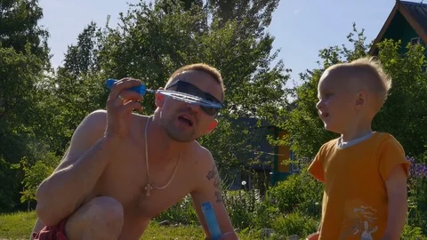 Father with his small son blowing bubbles outdoors in summer slow motion Stock-Footage 80085580