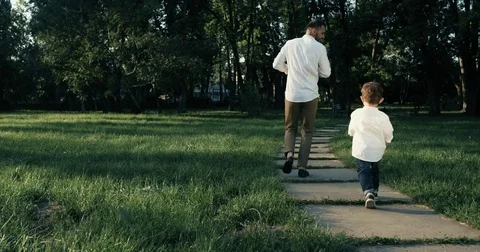 Father with his son jogging in the park, slow motion. 4k. Stock Footage