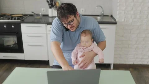 Father holding baby while working and talking on phone Stock Footage 325323087