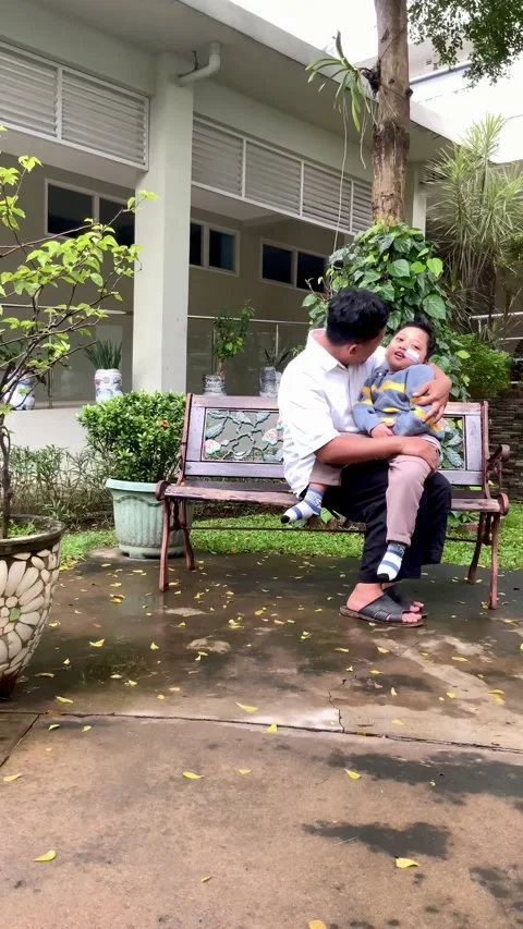 Father Holding Child with Special Needs on Bench Stock Footage 328634450