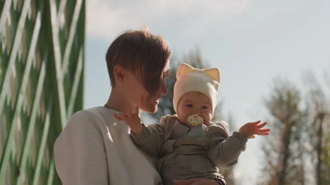 Father interacts with infant outdoors. Parent engages with child in park setting 動画素材 330431953