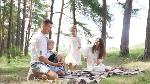 Father juggles with cones from a pine tree. Family picnic with two kids. Slowmo Stock Footage 205384139