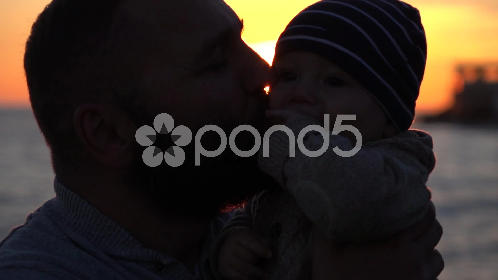 Father kissing baby during sunset