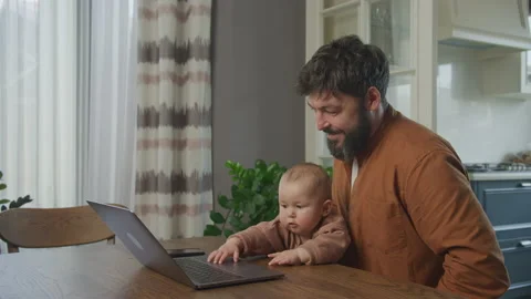 Father kissing his son while working on a laptop computer Stockbeeldmateriaal 200427742