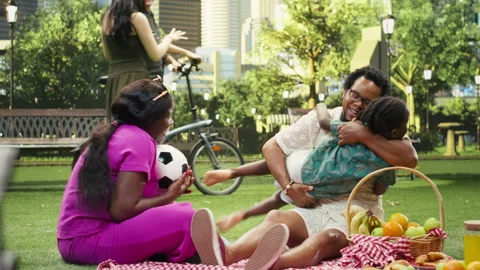 Father lifting and hugging boy while mother laughs on checkered blanket Stock Footage 341405124