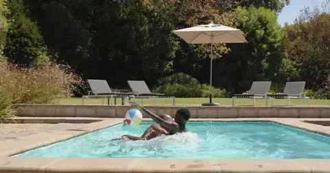 Father lifting son on shoulders in backyard pool, pushing into splash while Stock Footage 338436505