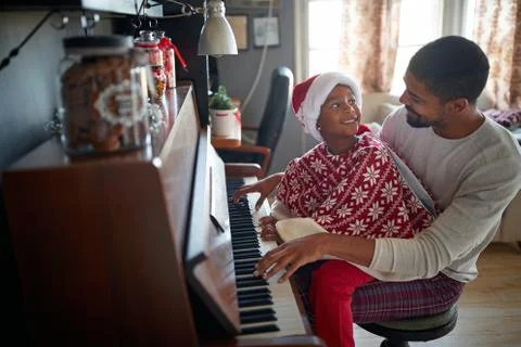 Father with little daughter on Christmas play music on piano. Stock Photos