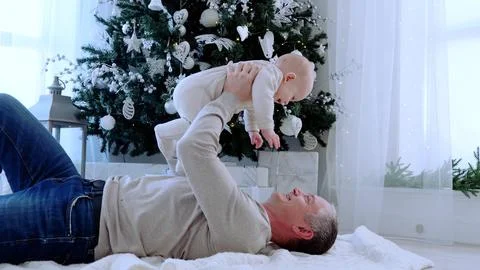 Father lying down on floor joyfully engaging with his little child creating Stock Photos
