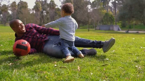 Father lying on grass, catching mixed-race son, playing together Stock Footage 104746576