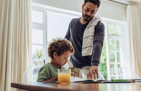 Father making his son do his school home work Stock Photos