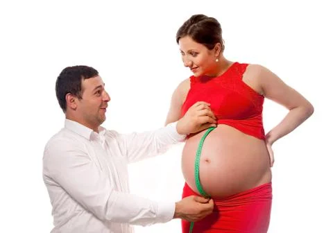 Father with measuring tape, checking belly size of pregnat wife Stock Photos
