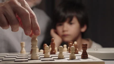 Father moves king as son captures rook in background during chess game Stock Footage 331095331