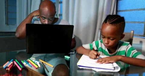 Father multi-tasking using computer laptop at home. Candid authentic and real Stock Photos
