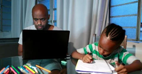 Father multi-tasking using computer laptop at home. Candid authentic and real Foto stock