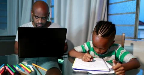 Father multi-tasking using computer laptop at home. Candid authentic and real Foto stock