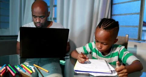 Father multi-tasking using computer laptop at home. Candid authentic and real Foto stock
