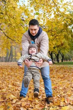 Father picking up son while standing in autumn park Stock Photos