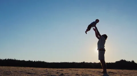 Father playing with his son - throws it high into the sky. In the rays of the Stock Footage 65762696