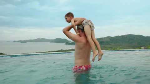 Father Playing with Two Children in Infinity Pool with Tropical Mountain View. Stock Footage 338370604
