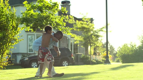 A father plays with his son in the grass on the lawn Stock Footage 33997770