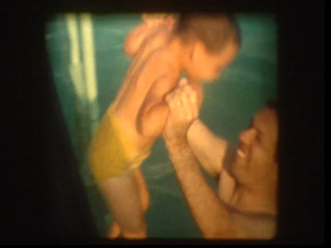 Father plays with young son in pool Vídeo Stock 1065780