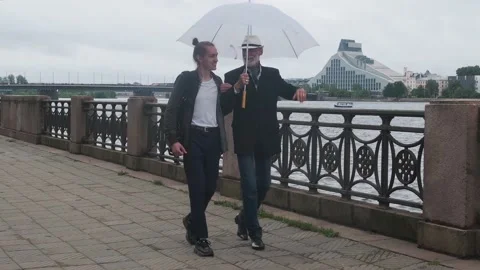 Father points to something walking with son under umbrella Stock Footage 136740504