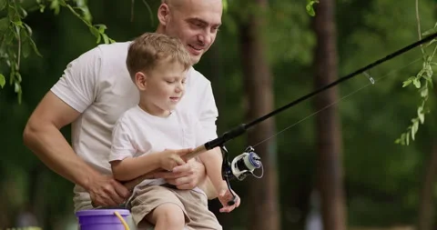 Father points toward fish wriggling at end of fishing line Video stock 322014066