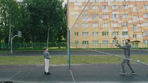 Father practicing volleyball techniques with young daughter at playground Stock Footage 318874068