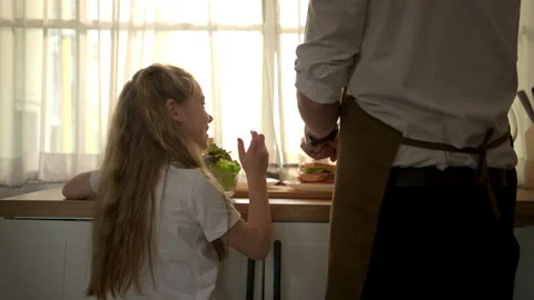 Father preparing a healthy breakfast while his daughter sits on the kitchen 動画素材 340937527