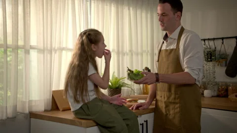 Father preparing a healthy breakfast while his daughter sits on the kitchen Stock-Footage 340938368