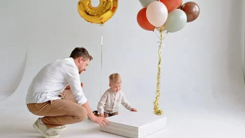 Father Presenting Large Gift to Toddler Indoors on White Background Stock Footage 307310334