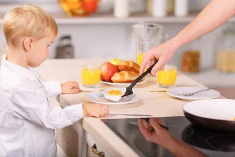 Father in the process of serving fried eggs Stock Photos