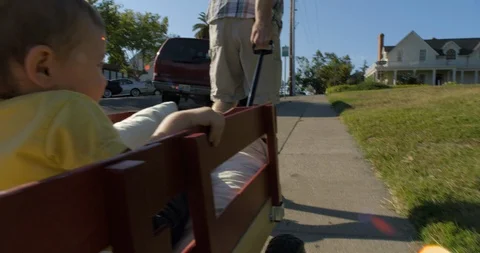 Father pulling along his two young sons in a cart Stock Footage 88372455