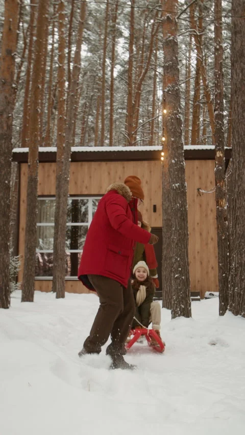 Father Pulling Daughter on Sled, Falling in Snow near Cabin Stock Footage 341864848