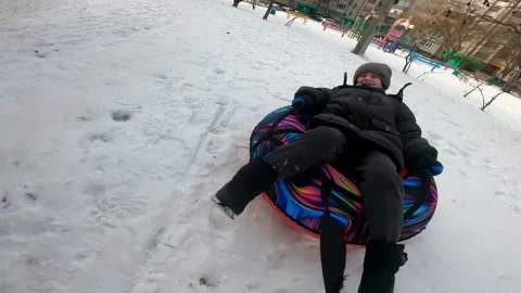 Father pulling his six year old son on an inflatable snow ride in winter Video stock 326156465