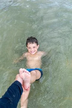 Father pulling his son's leg on the beach. Stock Photos