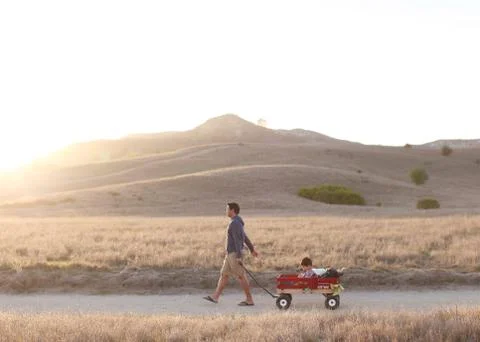 Father pulling son in cart Stock Photos