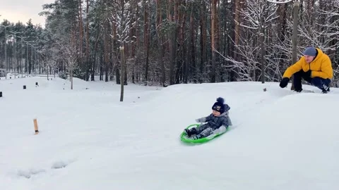 The father pushes the child down the slide on a sled Stock Footage 169014253